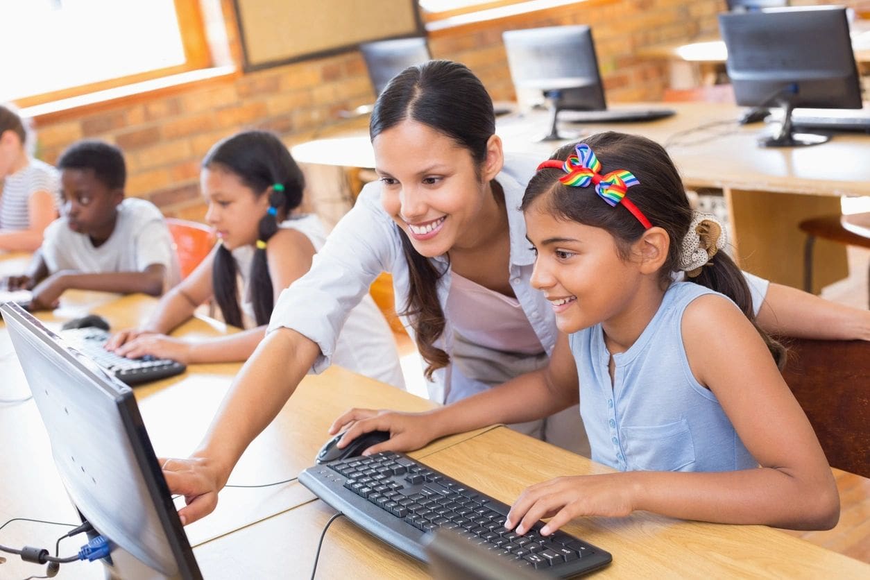 A woman and two girls are using computers.